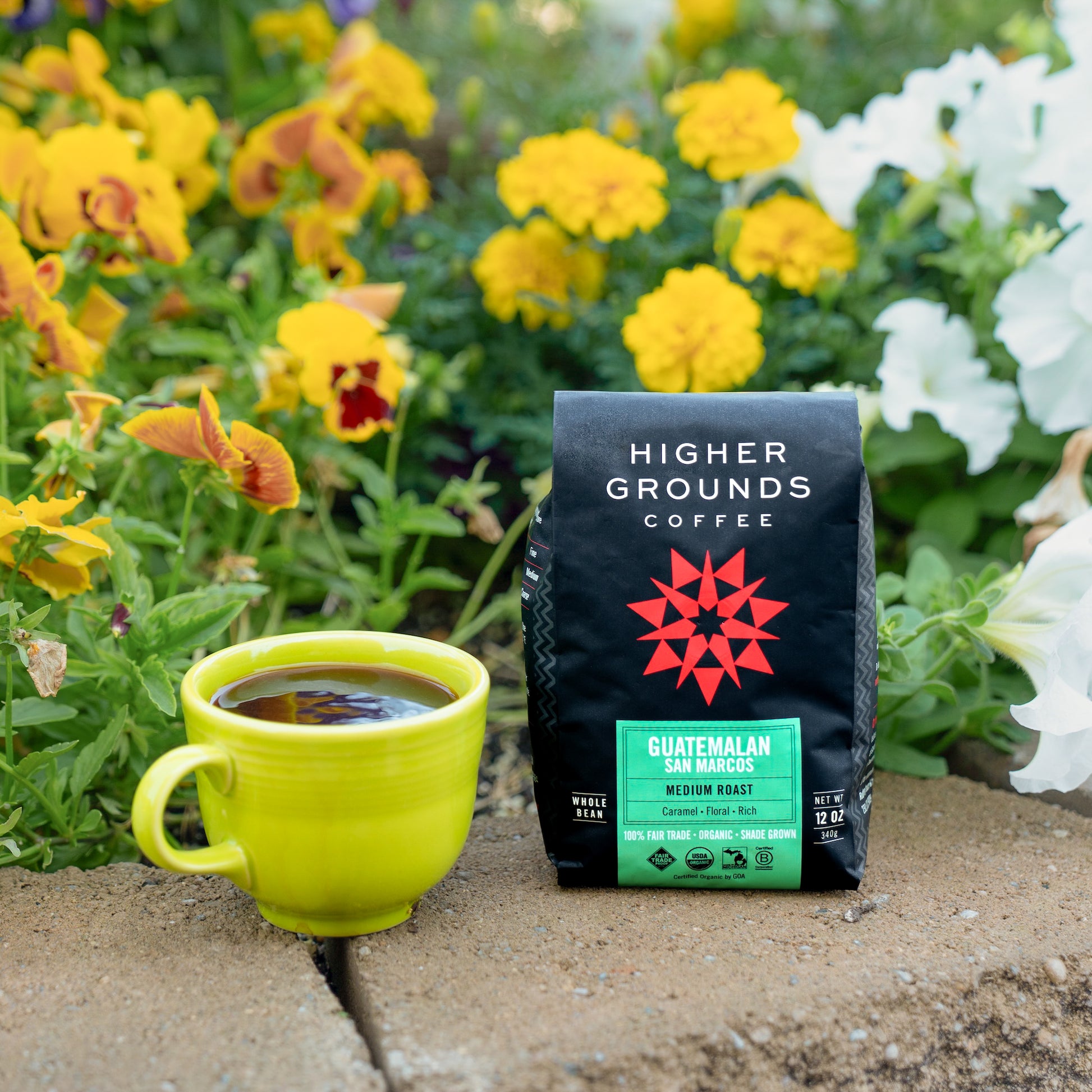 Mug of coffee next to a Higher Grounds Coffee Guatemalan San Marcos bag, with flowers 